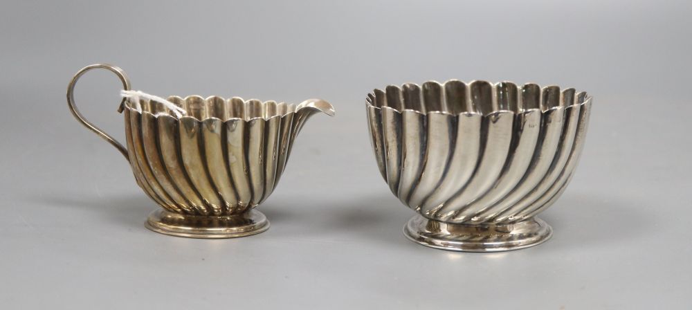 A silver wrythen embossed sugar bowl, Birmingham 1905 and a pear shaped milk jug, with broken scroll handle on collet base,